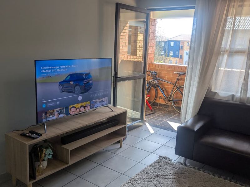 A living room area featuring tiled flooring and direct access to an outdoor balcony through a sliding glass door.