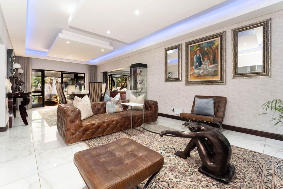 Spacious living room featuring modern recessed ceiling with ambient LED lighting, polished marble-look flooring, and large sliding glass doors leading to the outdoor area.