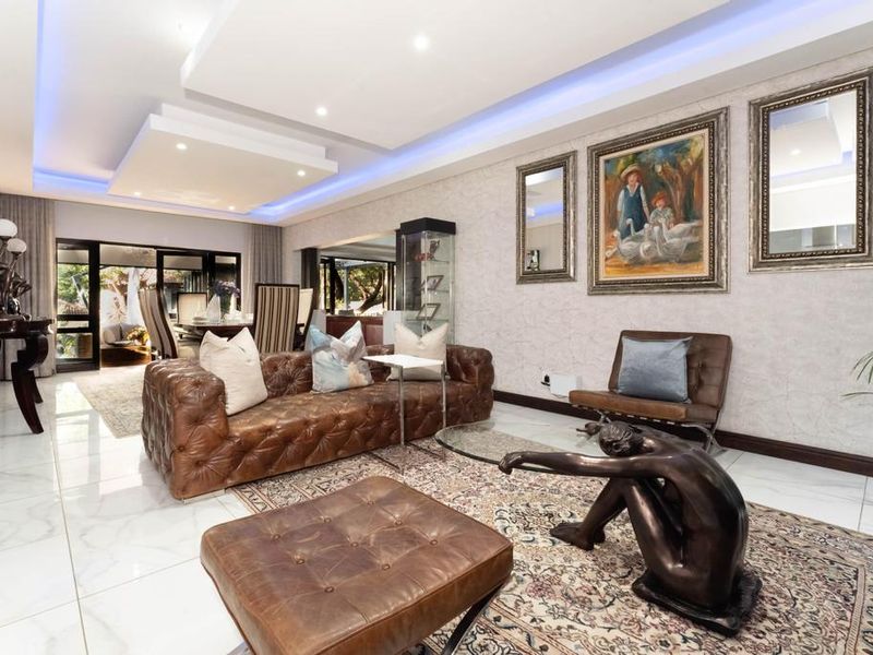 Spacious living room featuring modern recessed ceiling with ambient LED lighting, polished marble-look flooring, and large sliding glass doors leading to the outdoor area.