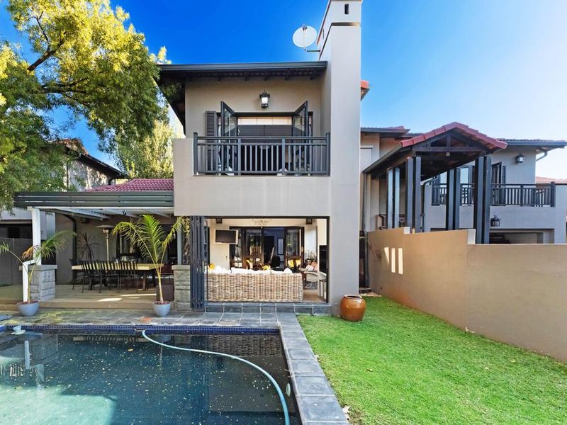 Rear view of the property featuring a swimming pool, covered patio area, and an upper-level balcony with modern architectural finishes.