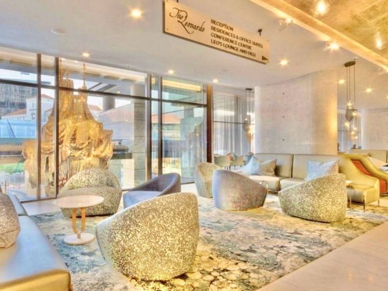 A modern, high-end apartment lobby or lounge area featuring floor-to-ceiling windows, polished marble flooring, and recessed lighting in a luxury residential building.