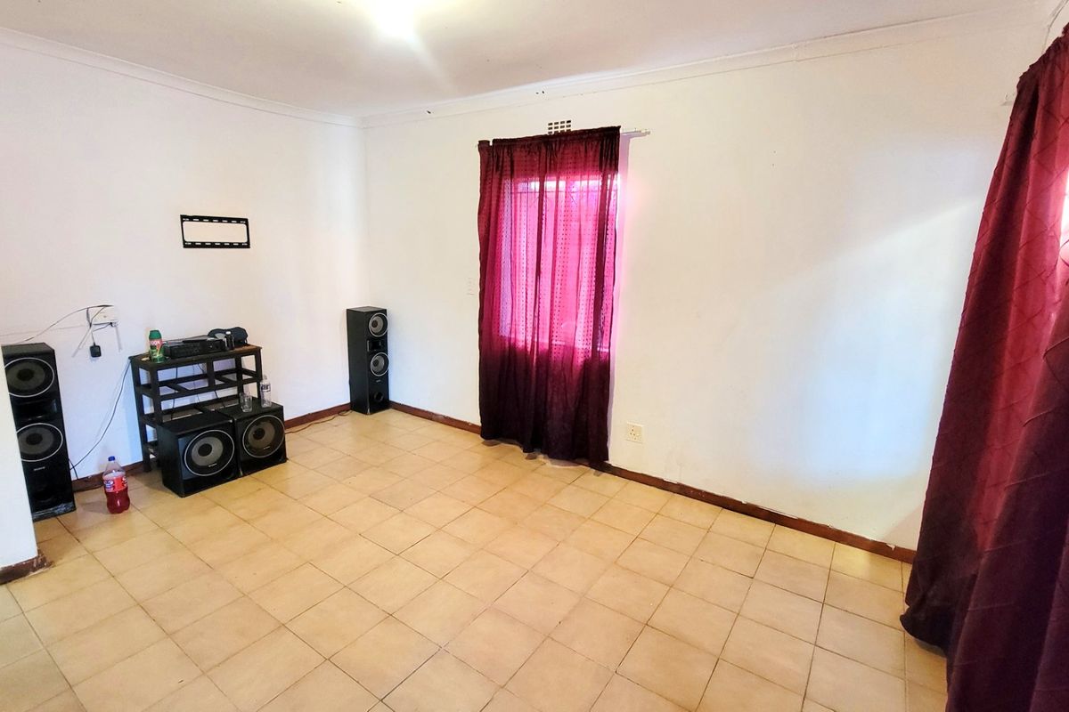 A simple living room featuring tiled flooring and a window with curtain fixtures, offering a blank canvas for personalization.