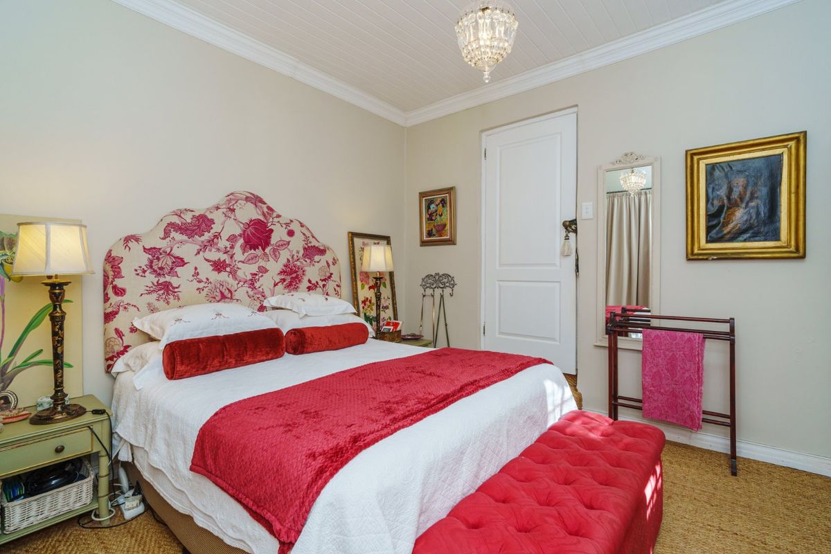A well-maintained bedroom featuring a classic tongue and groove ceiling, elegant crown molding, and a traditional panel door.