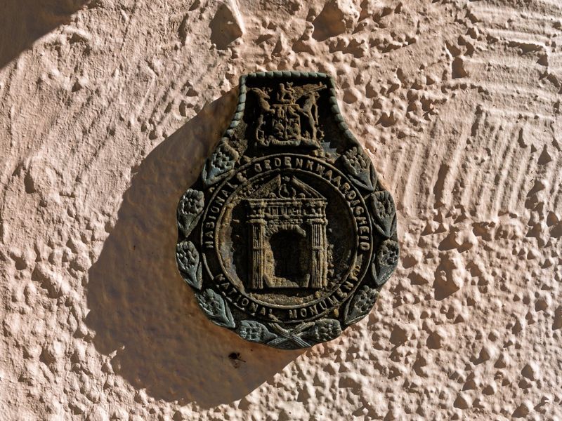 A close-up view of a National Monument plaque mounted on a textured exterior wall.