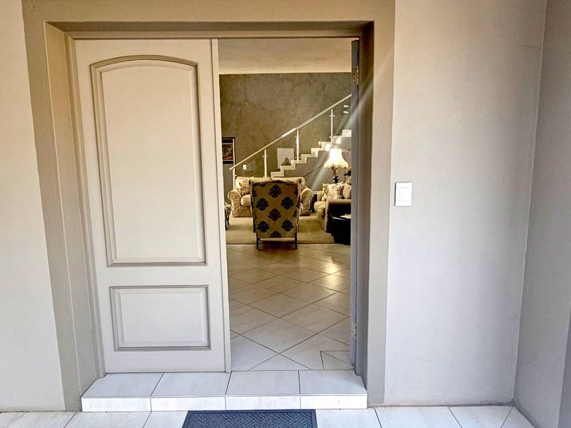 View through the main entrance door into the interior living area, featuring tiled flooring and a staircase with a metal balustrade.