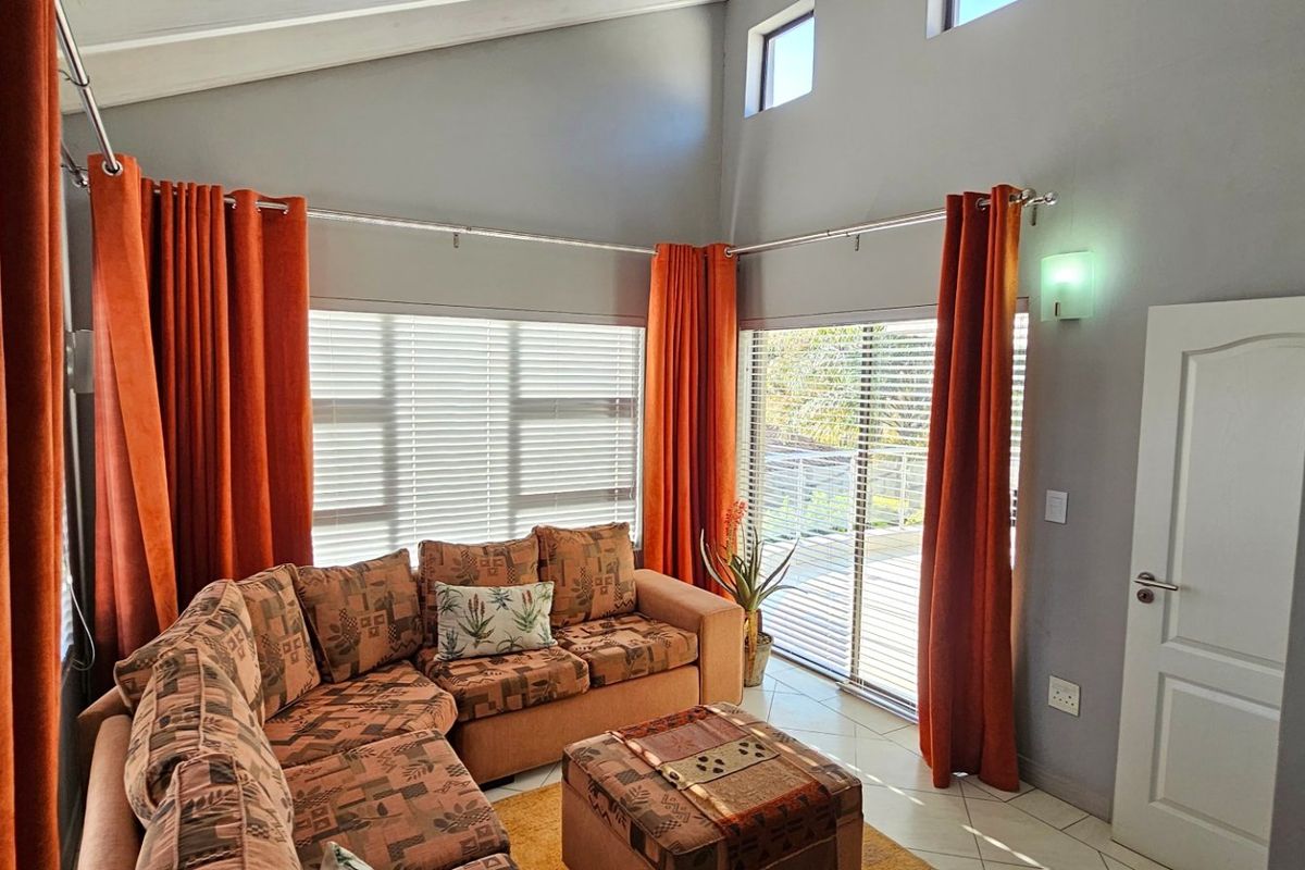 Spacious living room featuring a high vaulted ceiling, tiled flooring, and large sliding glass doors that provide access to an outdoor area.