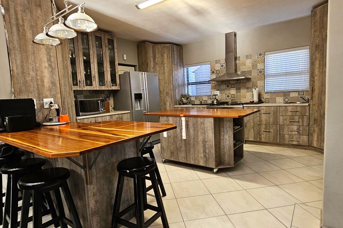 A well-appointed kitchen featuring wood-look cabinetry, a central island with a wooden countertop, a breakfast bar, and a decorative tiled backsplash.