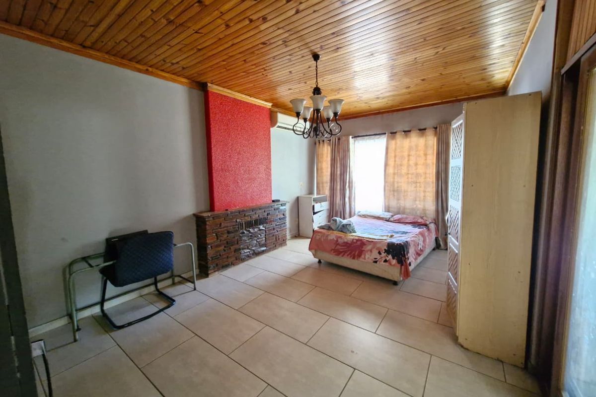 Spacious bedroom featuring tiled flooring, a timber-clad ceiling, and a prominent stone-clad fireplace feature wall.