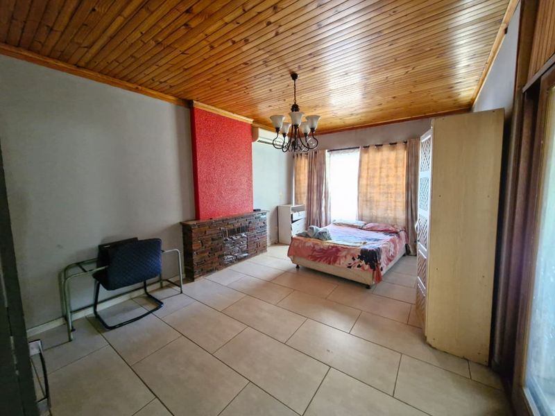 Spacious bedroom featuring tiled flooring, a timber-clad ceiling, and a prominent stone-clad fireplace feature wall.