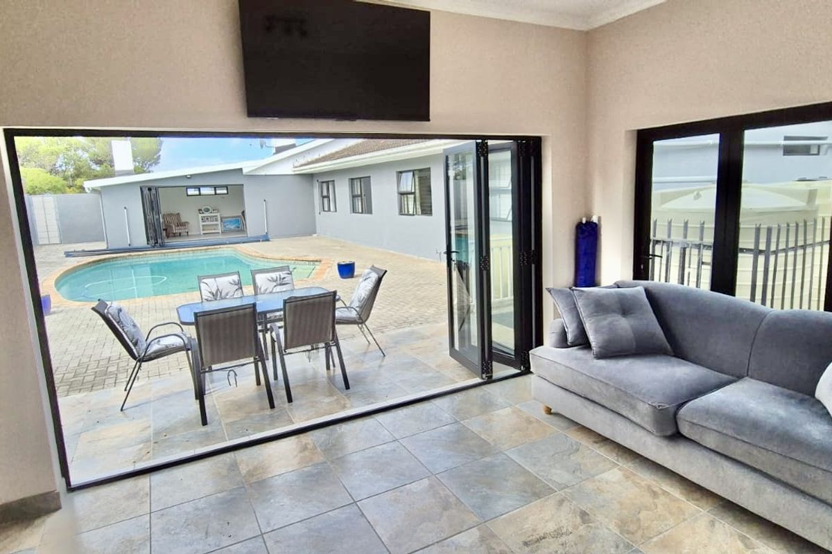 Bright living room featuring large bi-fold doors that open onto a paved patio and pool area, creating a seamless indoor-outdoor flow.