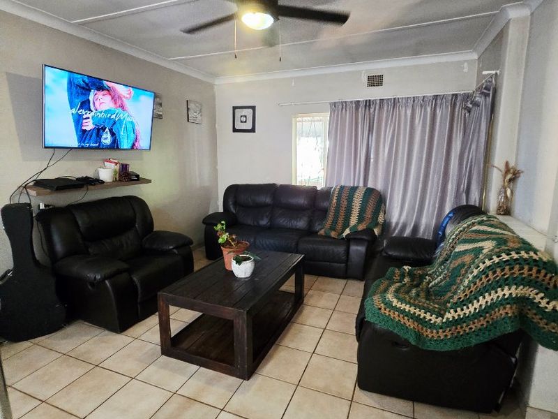 A living room featuring ceramic floor tiles, a ceiling fan, and cove cornicing. The space offers a functional layout for relaxation.