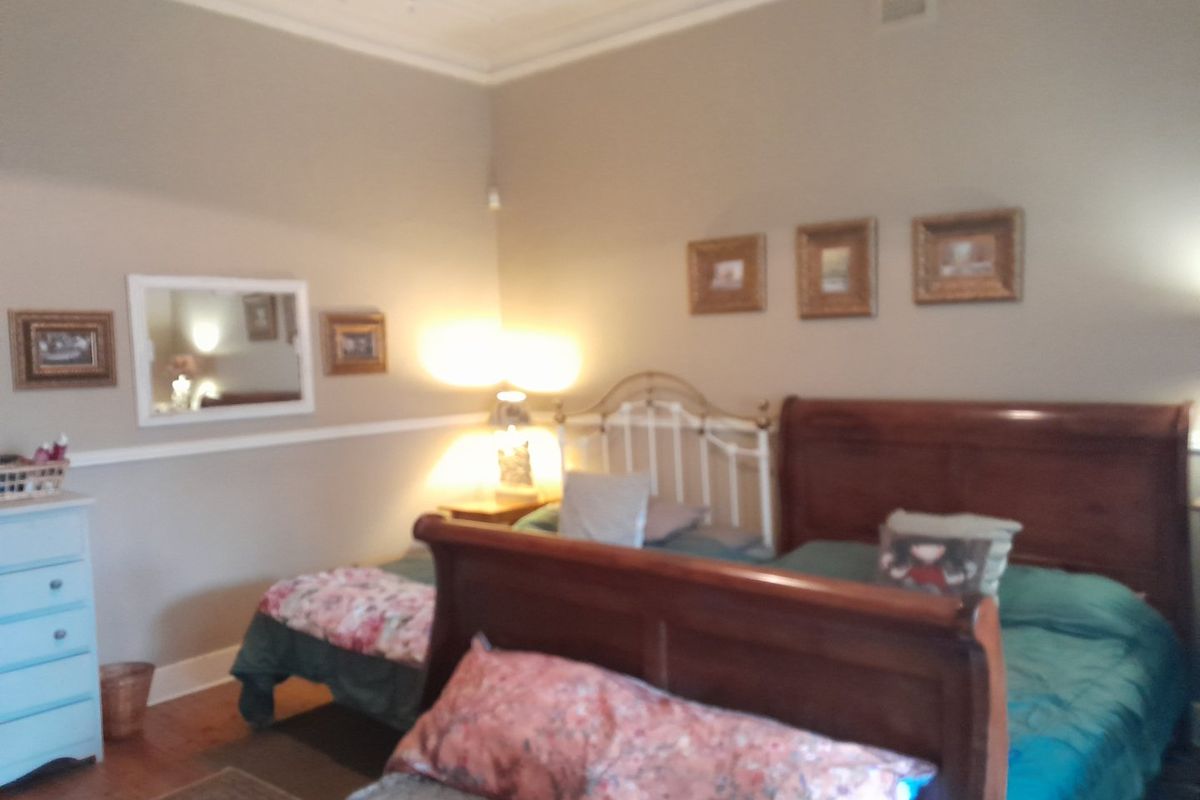 A bedroom featuring classic timber flooring, ornate ceiling detailing, and a traditional picture rail, offering a character-filled space.