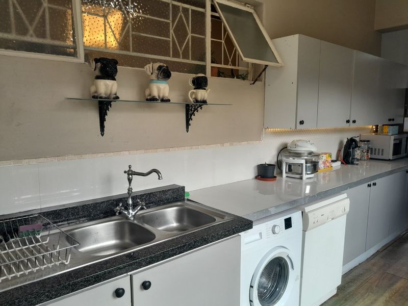 A functional kitchen featuring a double stainless steel sink, granite countertops, ample built-in cabinetry, and under-cabinet lighting.