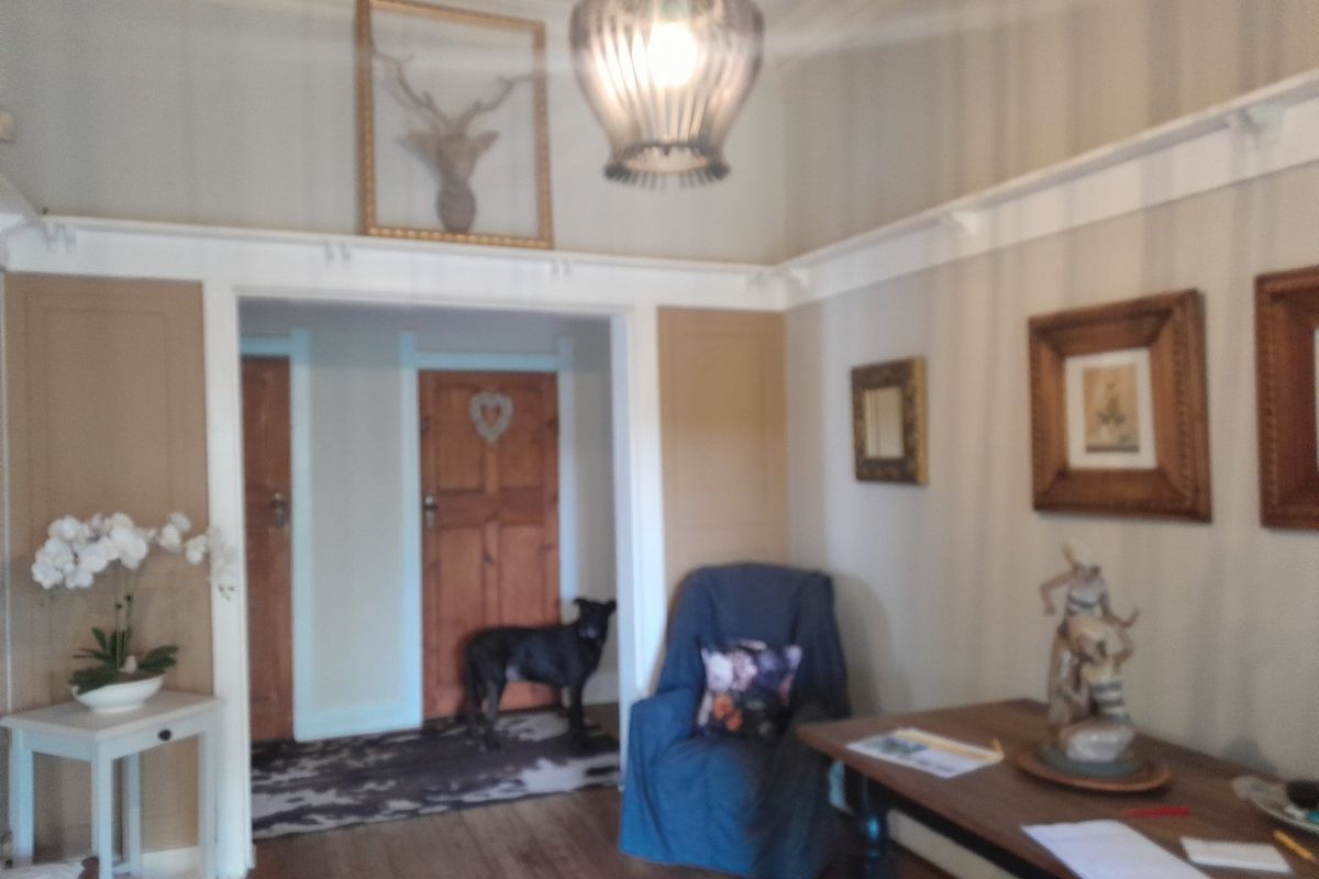 A living room featuring timber flooring, picture rails, and classic timber doors, offering a traditional aesthetic with potential for modern updates.
