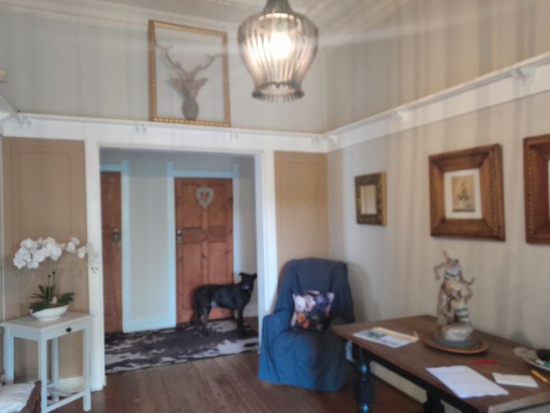 A living room featuring timber flooring, picture rails, and classic timber doors, offering a traditional aesthetic with potential for modern updates.