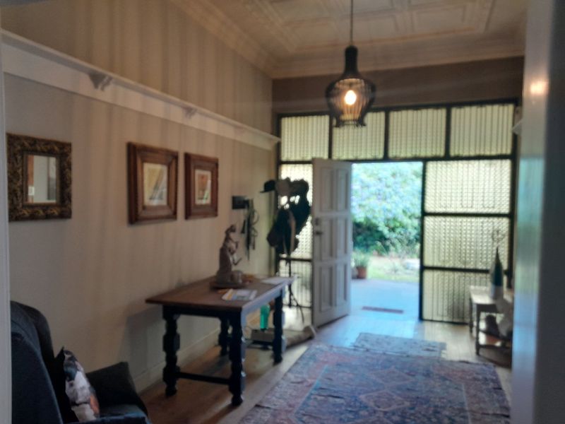 A character-filled entrance hall featuring a decorative ceiling, picture rails, and a timber door opening to an outdoor area.