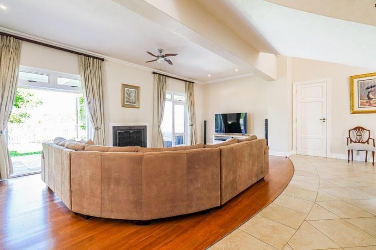 Spacious living room featuring a fireplace, ceiling fan, and a blend of hardwood and tiled flooring with direct access to the outdoor area.
