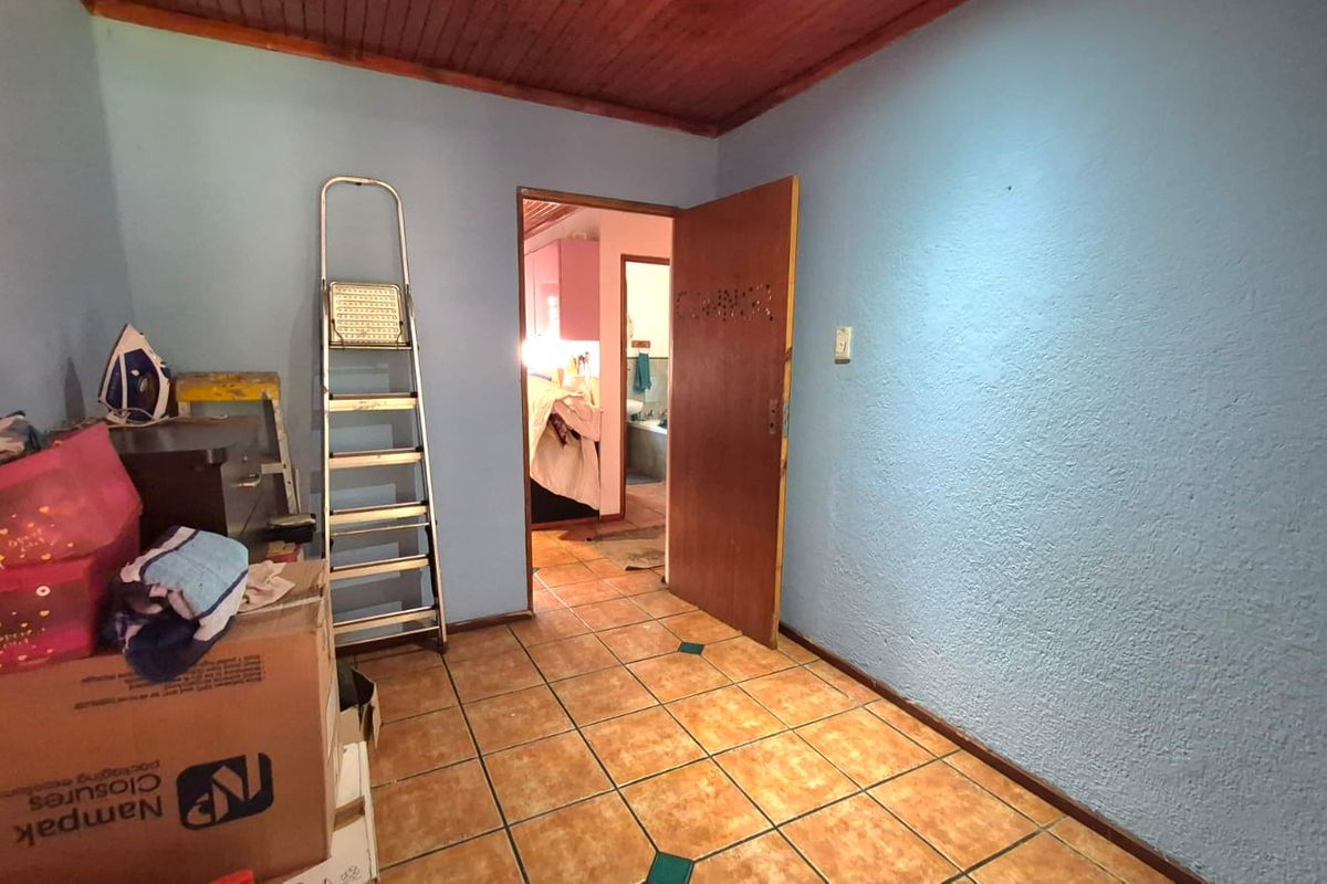 A bedroom featuring ceramic floor tiles and a timber ceiling, showing signs of wear and requiring cosmetic updates.