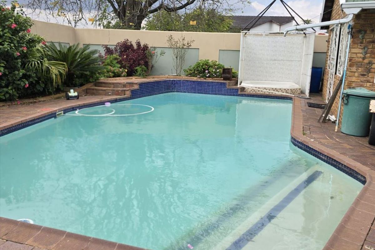 Outdoor pool area featuring a swimming pool with brick paving surround, boundary wall, and direct access to the main house structure.