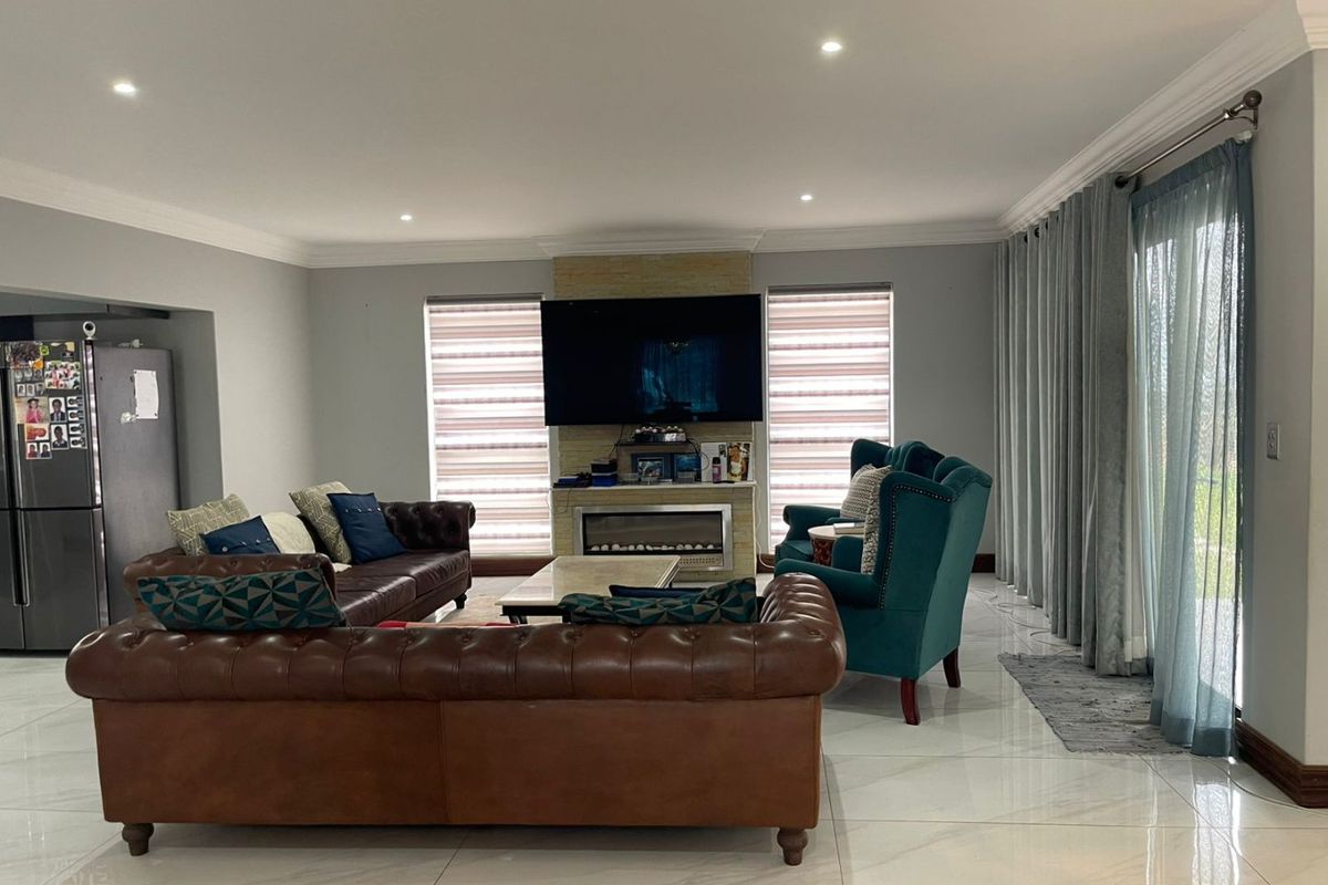 Spacious living room featuring a modern built-in fireplace with stone cladding, recessed downlighting, large format floor tiles, and sliding glass doors leading outdoors.