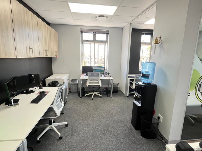 A modern commercial office space featuring built-in cabinetry, carpeted flooring, and a glass partition wall, providing a professional and functional work environment.