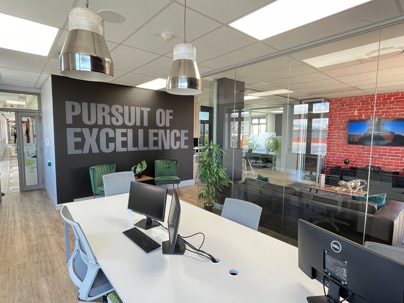Modern commercial office space featuring glass partitions, a contemporary brick feature wall, suspended ceilings, and a professional open-plan layout.