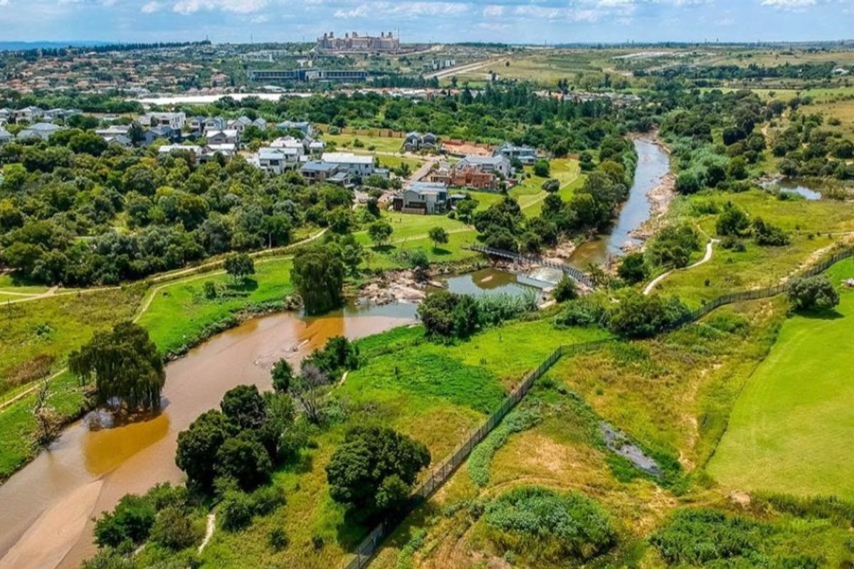 An aerial view of the residential estate featuring a river, lush greenbelt areas, and surrounding landscape.