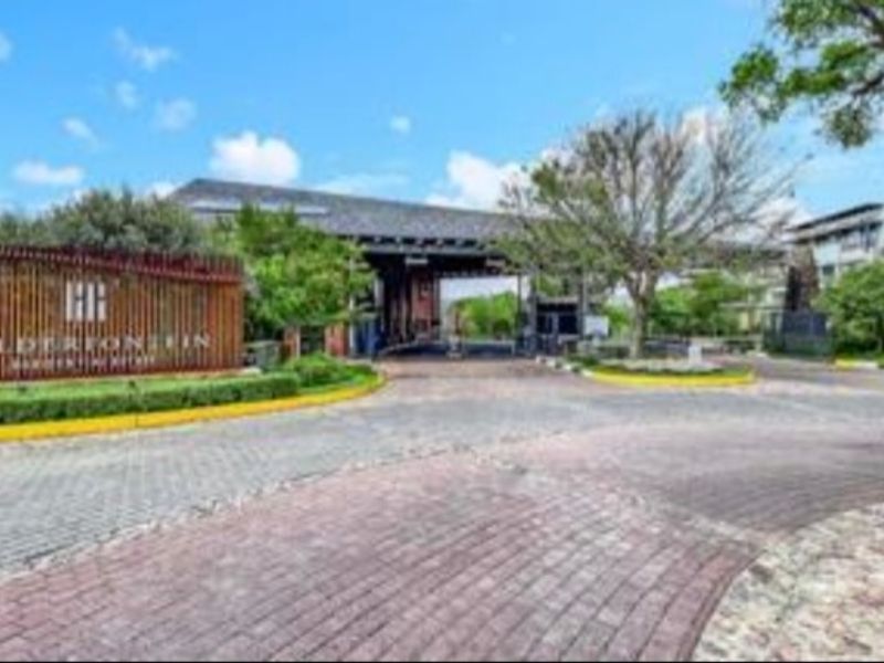 The main entrance and security gatehouse of the residential estate, featuring paved access and established landscaping.