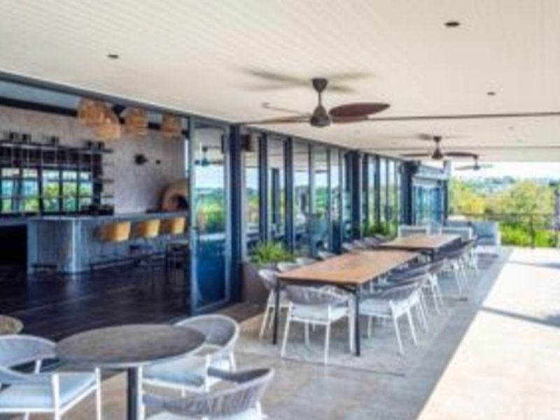 A spacious covered patio featuring a built-in bar, recessed lighting, ceiling fans, and large sliding glass doors, perfect for outdoor entertaining.