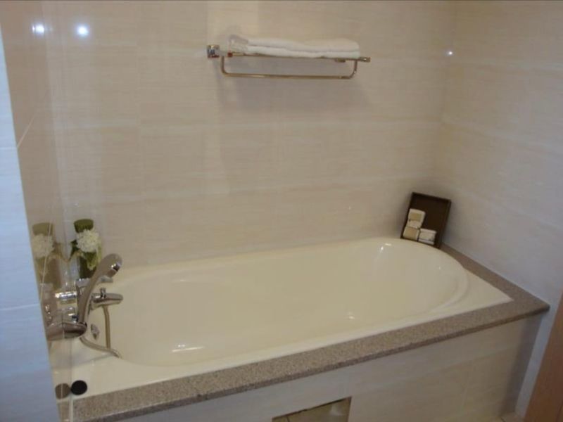 A clean bathroom featuring a built-in bathtub with chrome fixtures and neutral wall tiling.