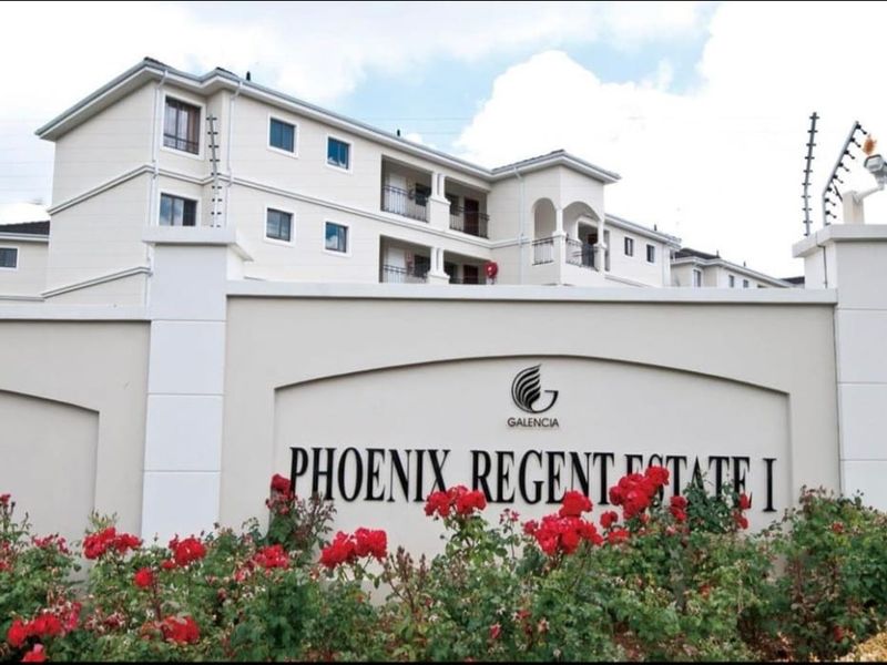Front entrance view of Phoenix Regent Estate I, featuring a secure perimeter wall, electric fencing, and multi-story residential apartment blocks.