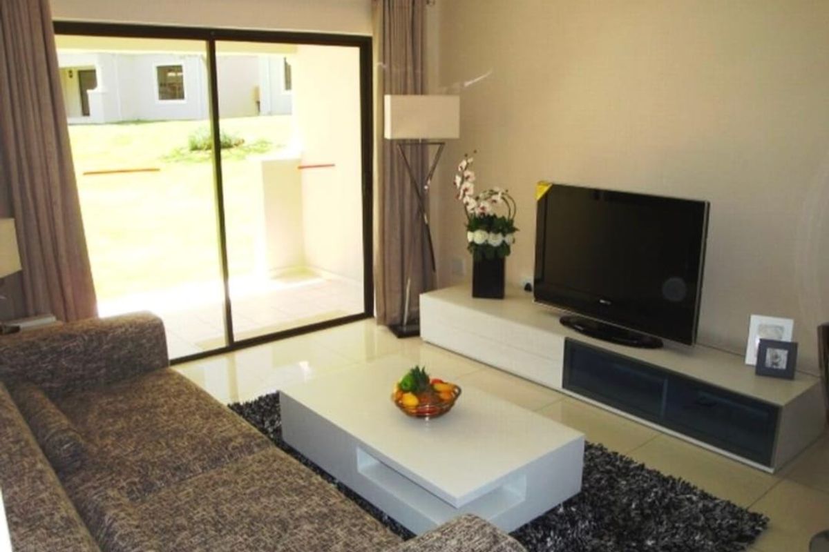 A well-lit living room featuring large sliding glass doors that provide direct access to the outdoor patio area.