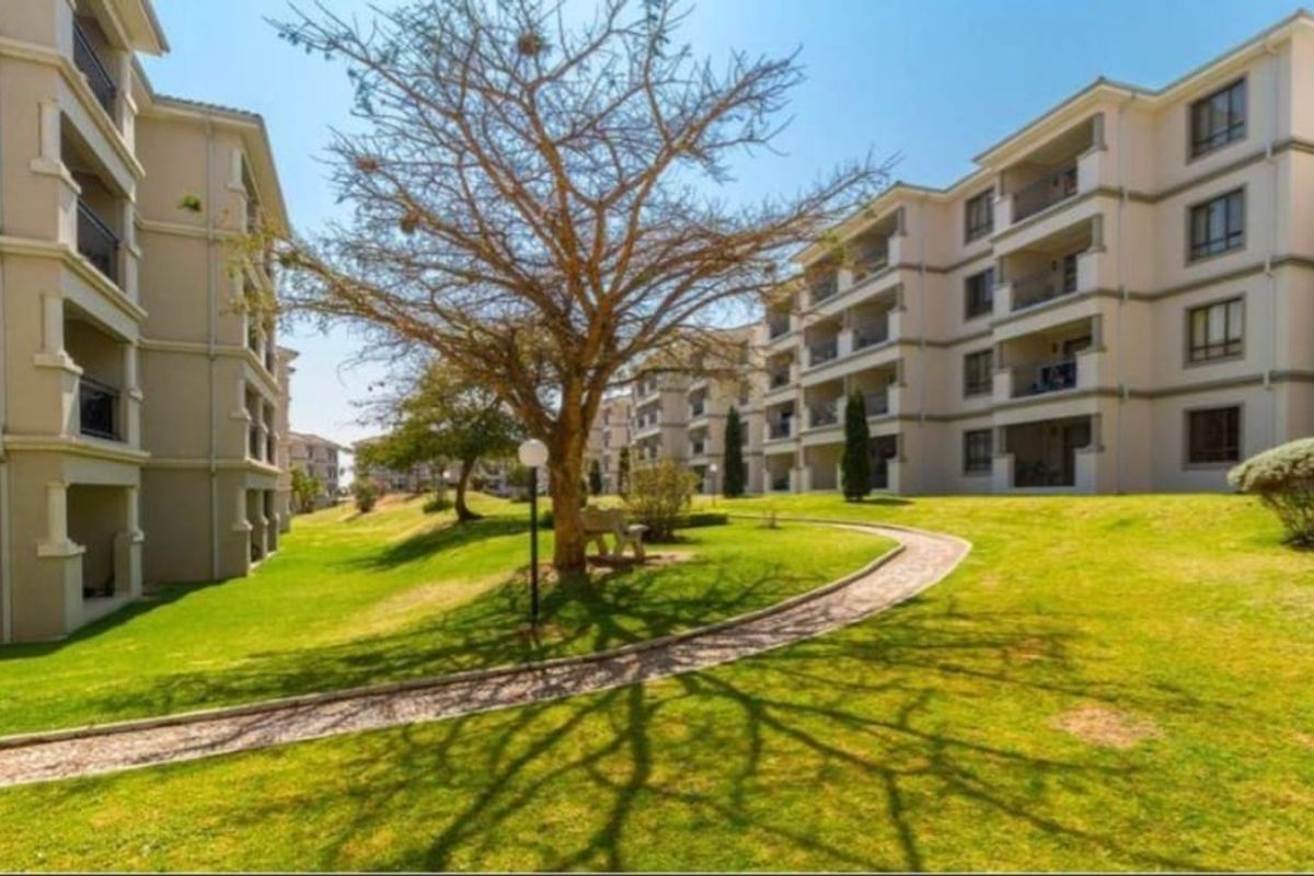 A well-maintained residential complex featuring multi-story buildings with balconies, surrounded by landscaped lawns and paved walkways.