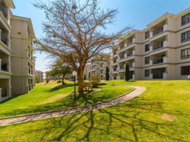 A well-maintained residential complex featuring multi-story buildings with balconies, surrounded by landscaped lawns and paved walkways.