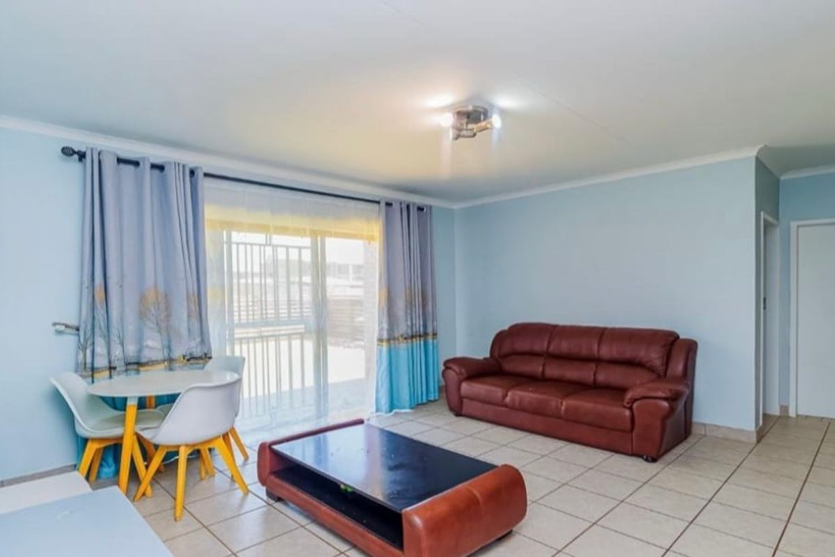 A bright living room featuring tiled flooring, a ceiling light fixture, and a sliding glass door providing access to the exterior.