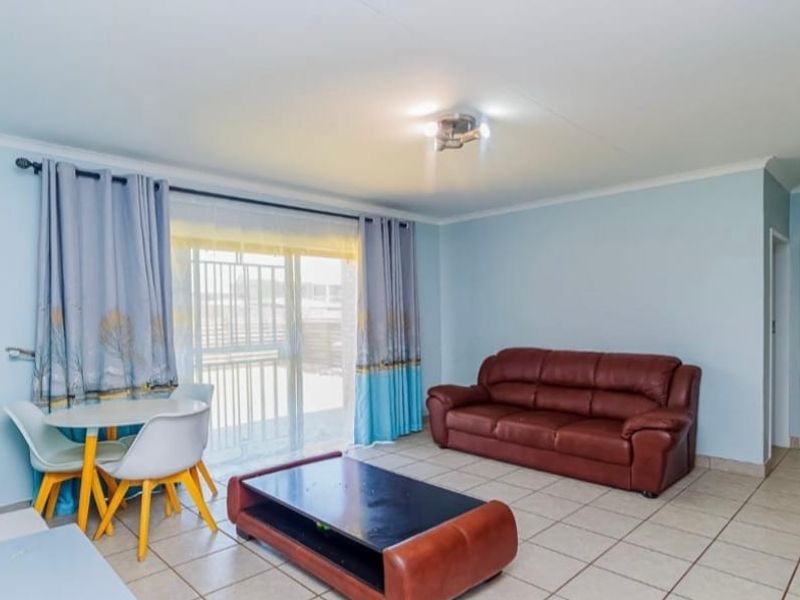 A bright living room featuring tiled flooring, a ceiling light fixture, and a sliding glass door providing access to the exterior.