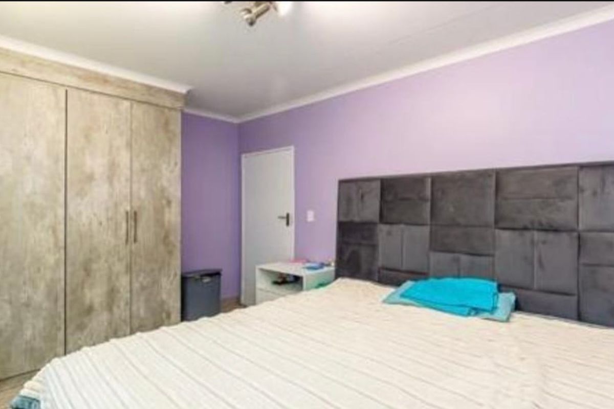 A bedroom featuring built-in wooden cupboards and purple painted walls.