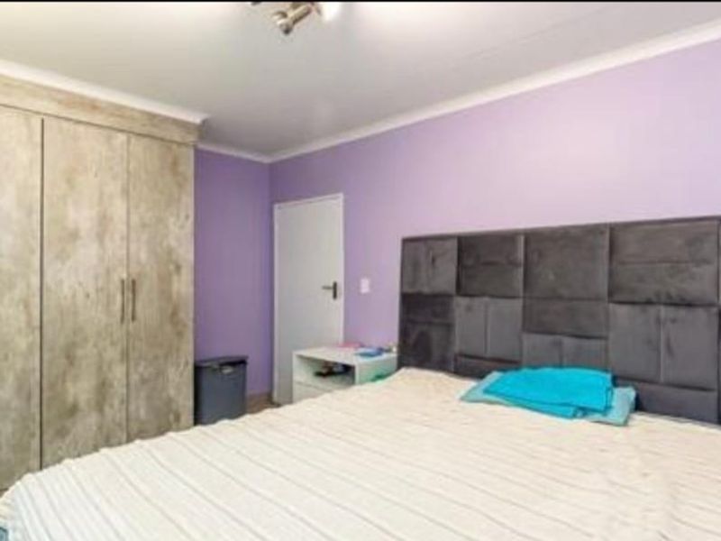 A bedroom featuring built-in wooden cupboards and purple painted walls.