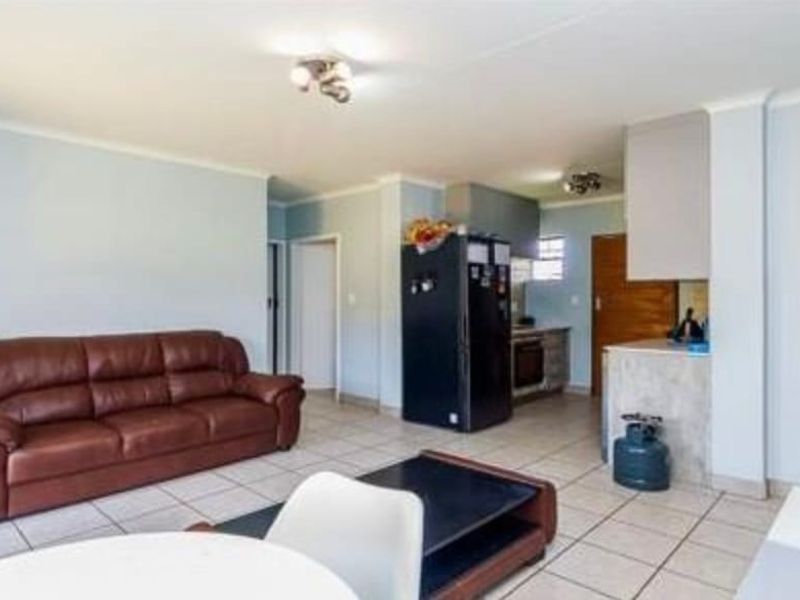 Open-plan living area featuring tiled flooring and a functional kitchen space with built-in cabinetry, oven, and extractor fan.