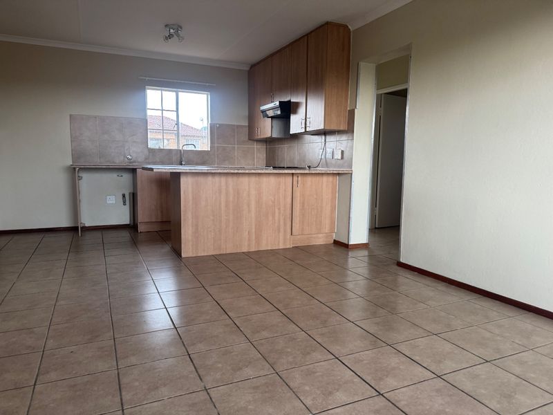 Open plan kitchen area featuring laminate cabinetry, tiled flooring, and a tiled backsplash, offering a functional layout ready for modern updates.