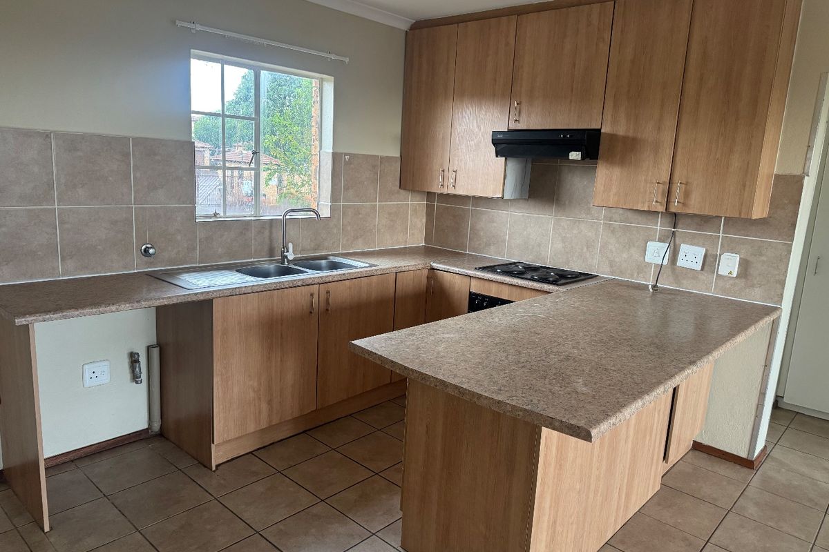A functional kitchen featuring laminate cabinetry, tiled backsplash, built-in hob with extractor fan, and a breakfast nook counter.