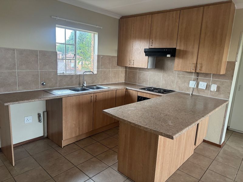 A functional kitchen featuring laminate cabinetry, tiled backsplash, built-in hob with extractor fan, and a breakfast nook counter.