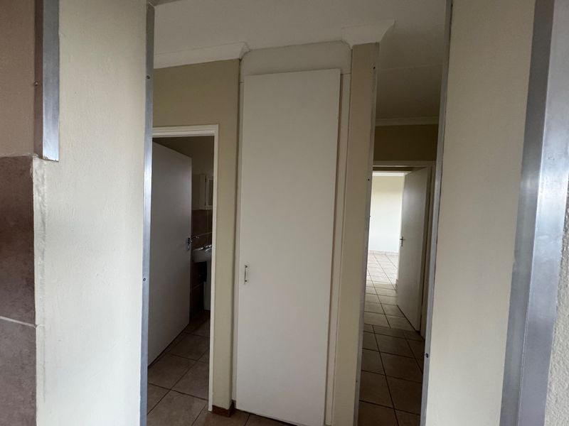 A functional hallway featuring tiled flooring, built-in storage cupboards, and access to adjacent rooms within the townhouse.