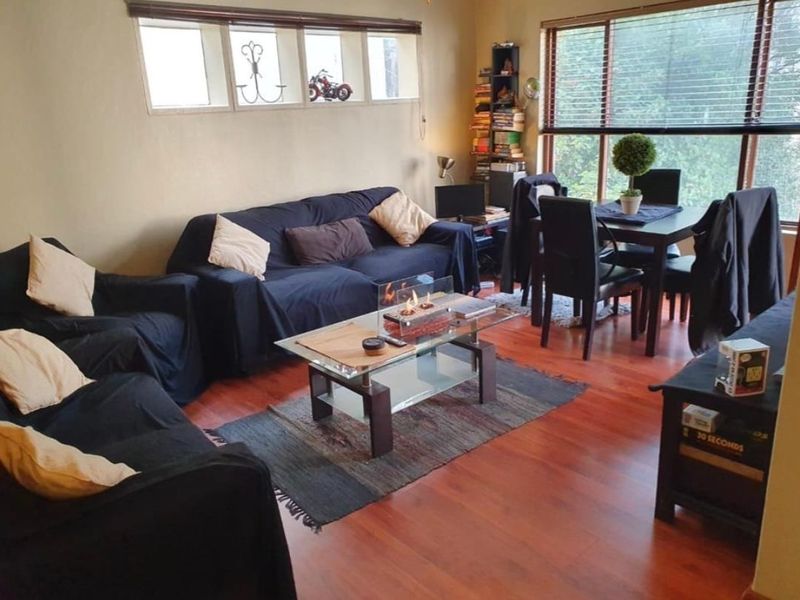 Open-plan living and dining area featuring laminate flooring and large windows with venetian blinds, providing a functional and well-lit space.