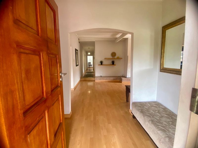 A bright and welcoming entrance hall featuring light laminate flooring and an arched transition leading into the main living area.