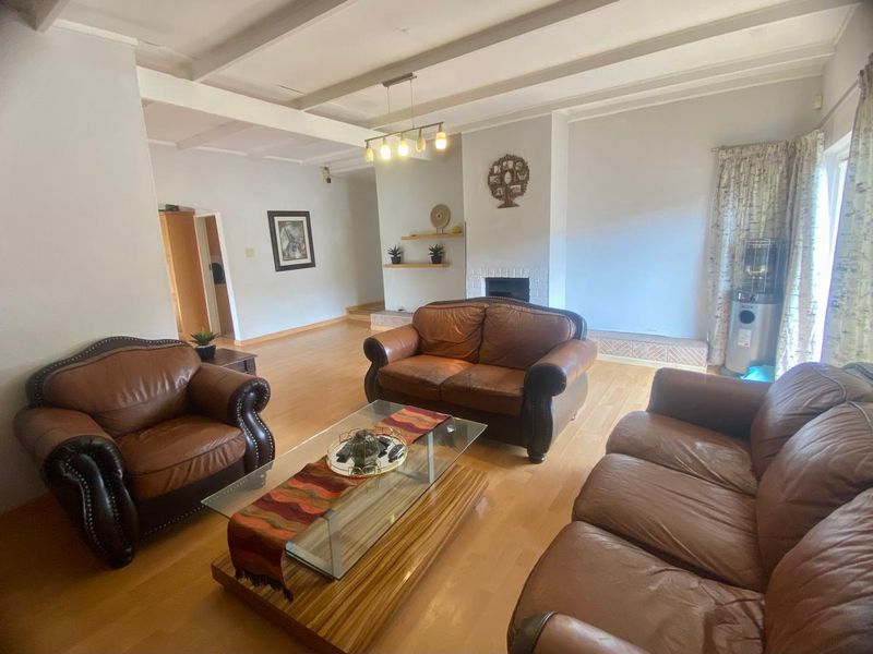 Spacious living room featuring exposed ceiling beams, laminate flooring, and a central fireplace with built-in shelving.