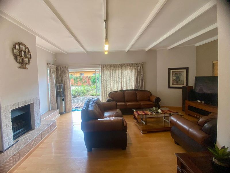 Spacious living room featuring a fireplace with a tiled hearth, exposed beam ceiling, and sliding glass doors leading to the outdoor patio area.