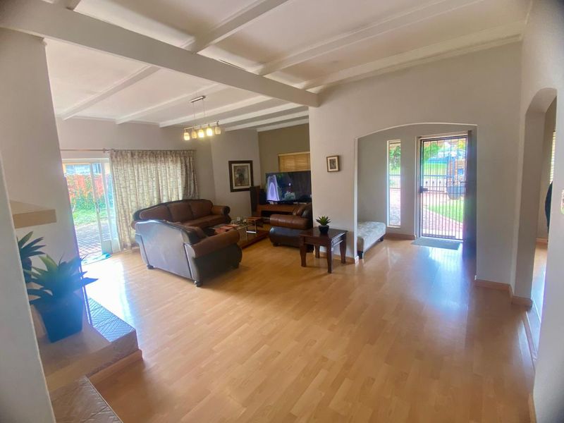 Spacious living room featuring laminate flooring, exposed beam ceilings, and direct access to the garden through a sliding glass door.