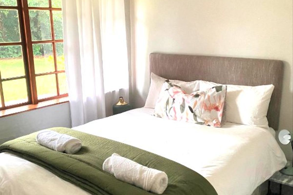 A cozy bedroom featuring a timber-framed window with natural light and neutral wall finishes.