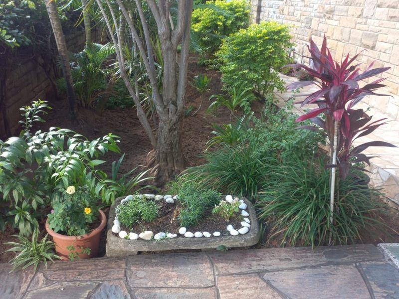 A well-maintained rear garden area featuring natural stone cladding on the building exterior and durable flagstone paving.